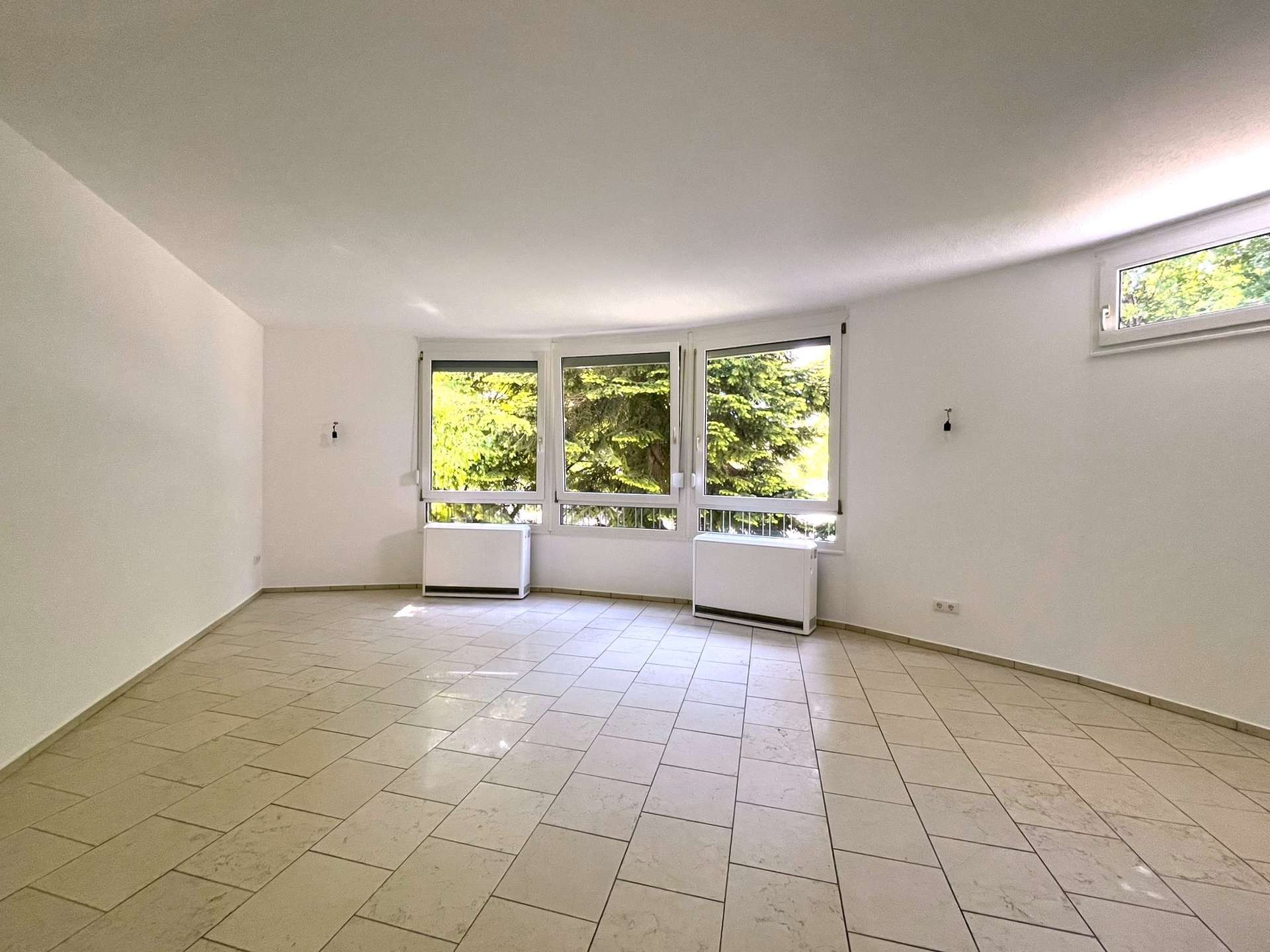 Helles Wohnzimmer mit großen Fenstern und Fliesenboden